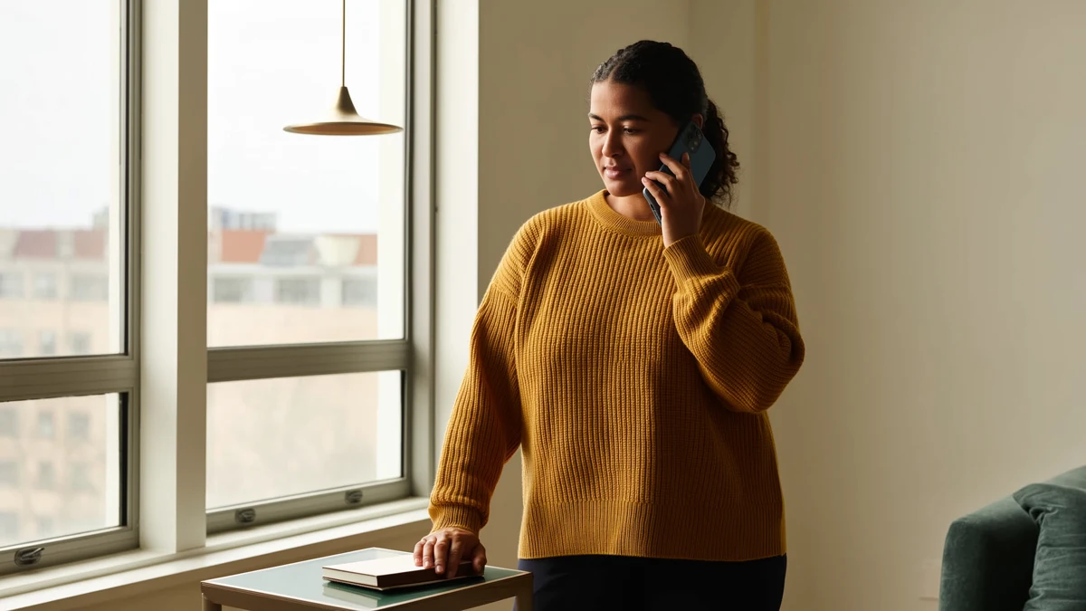 an adult making a private phone call beside a sunlit window