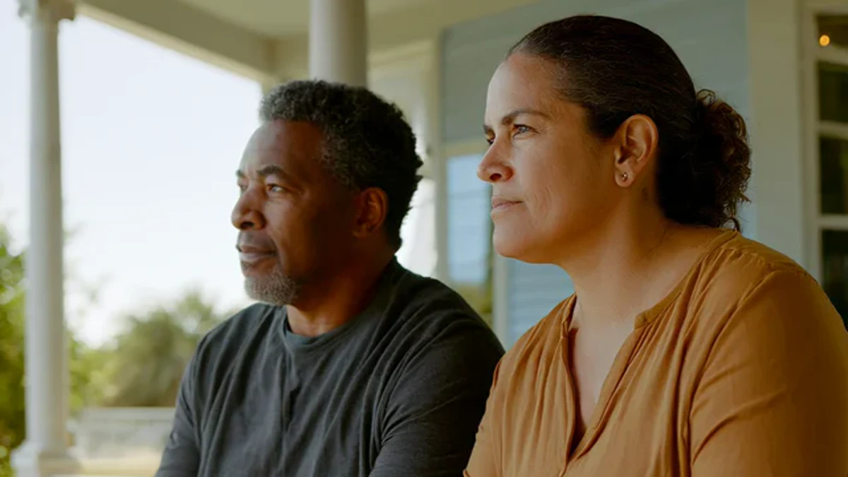 two adults seated together on a shaded porch in morning light