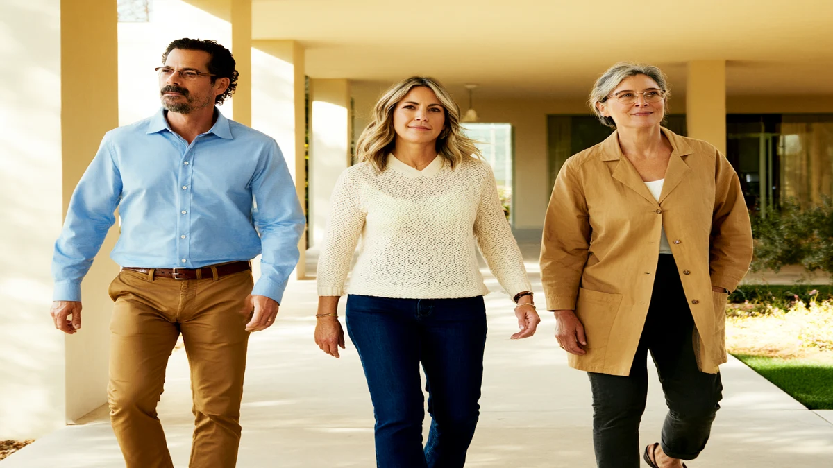 three adults walking together through a sunlit courtyard