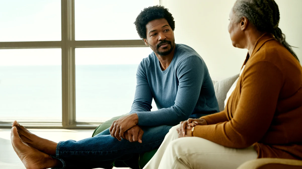 two adults in a calm conversation beside a sunlit window